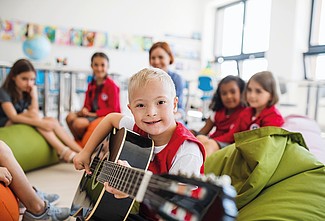 Kind mit Down-Syndrom spielt Gitarre