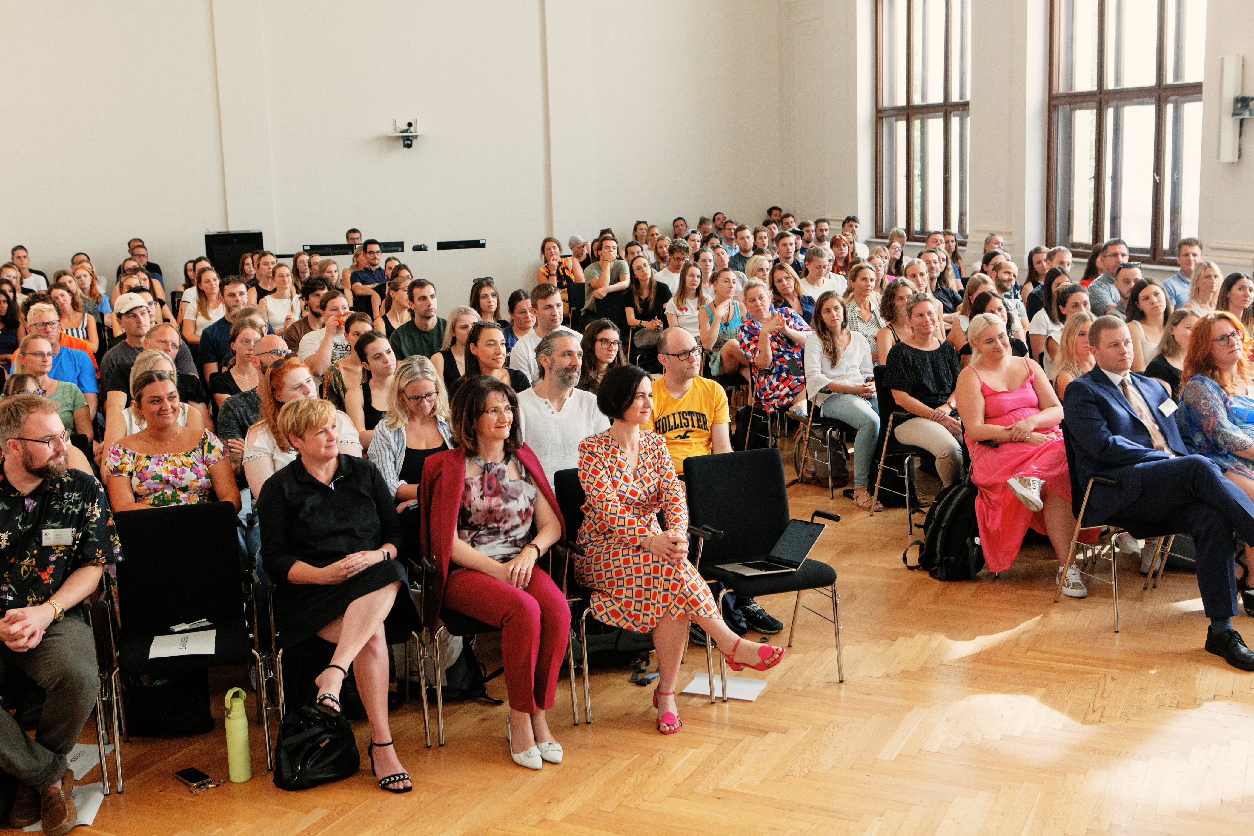 Berufseinsteiger*innen und Vortragende sitzen in der Aula 