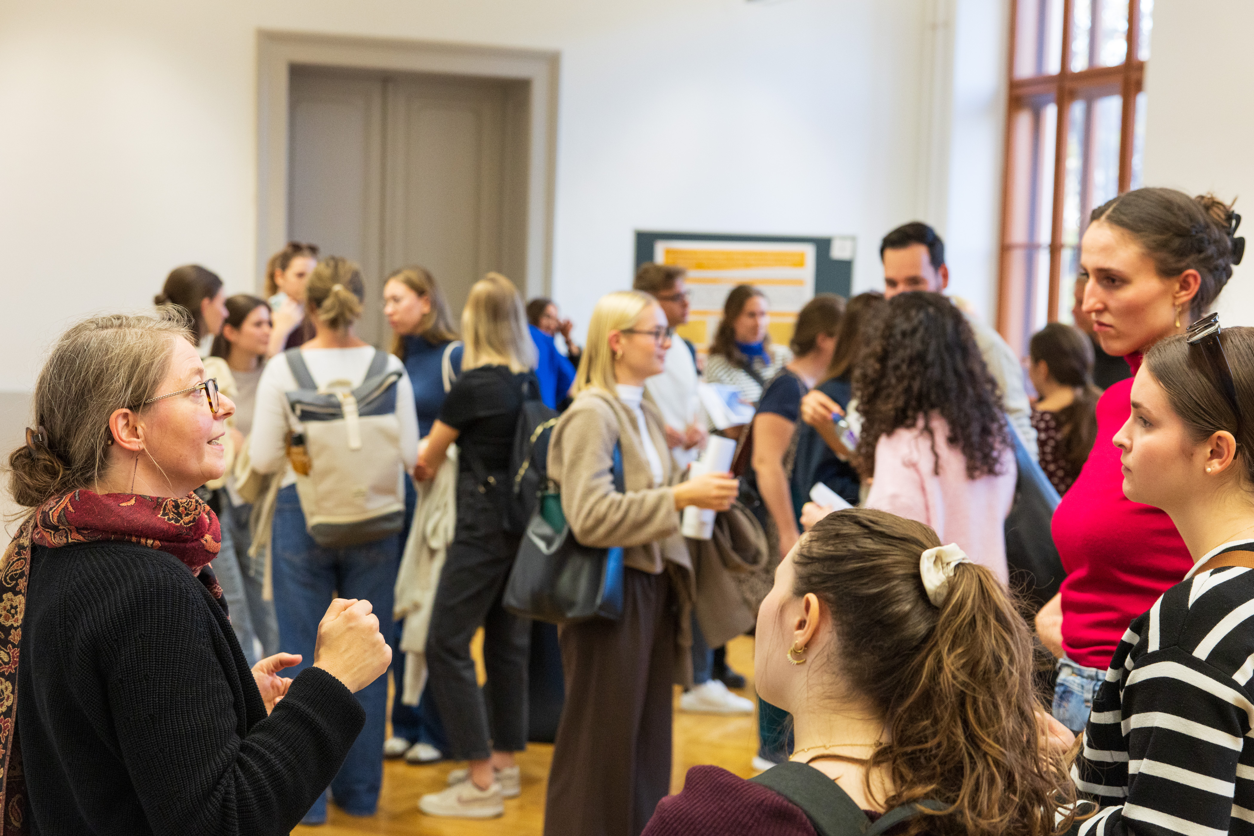 viele Personen stehen in einem Saal und unterhalten sich in kleinen Gruppen