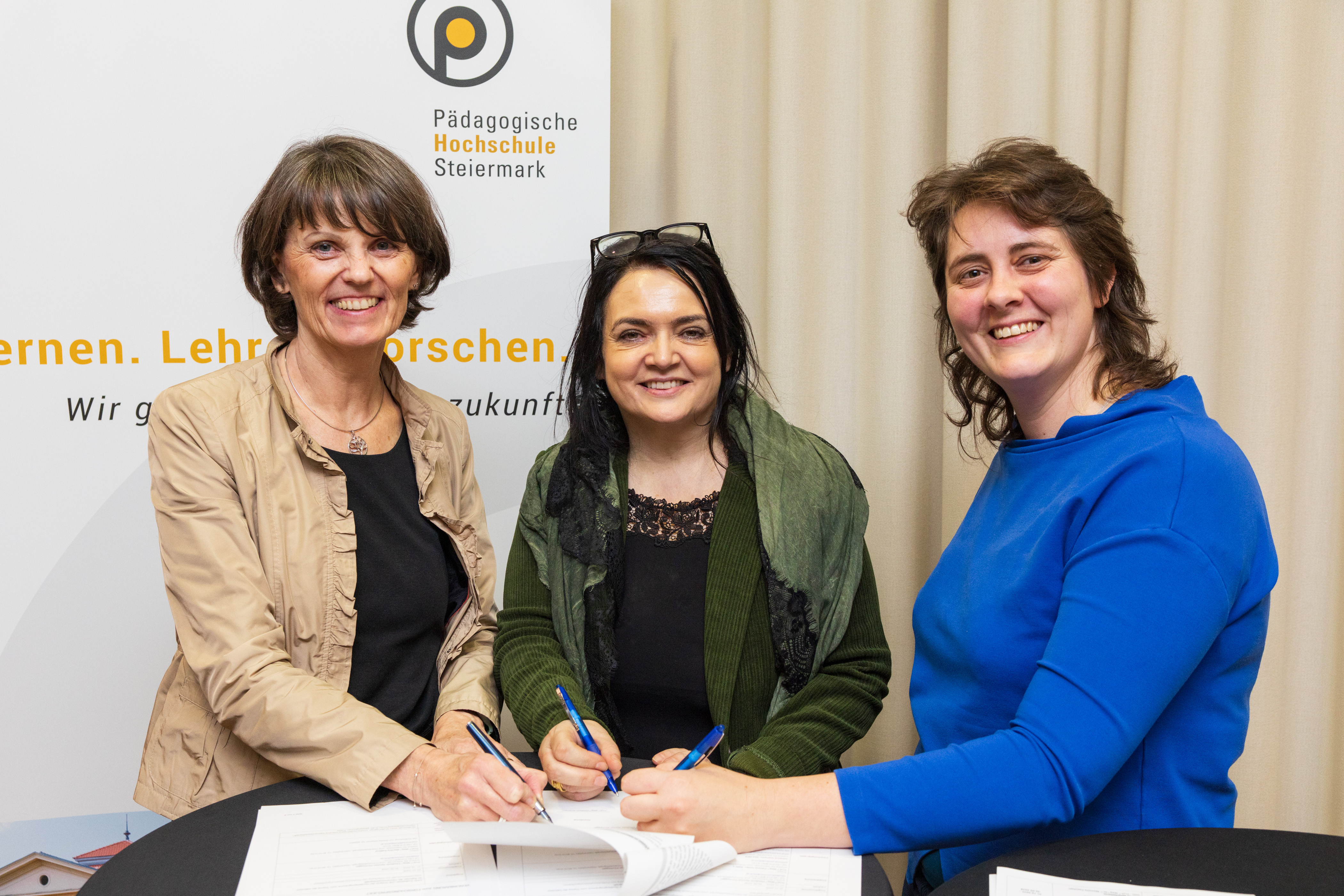 Drei Frauen unterschreiben einen Zettel