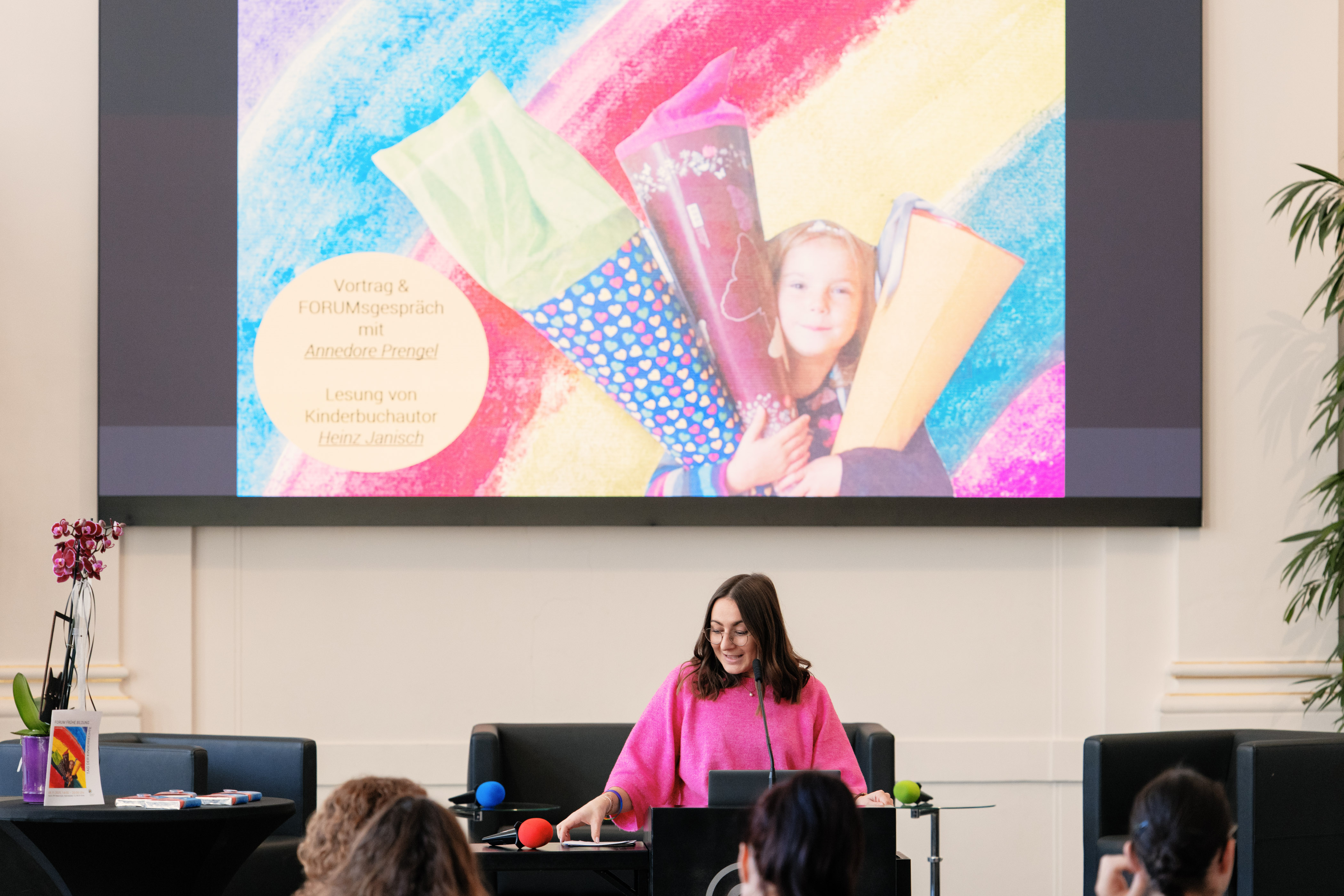 eine Frau steht auf der Bühne und spricht ins Mikrofon 