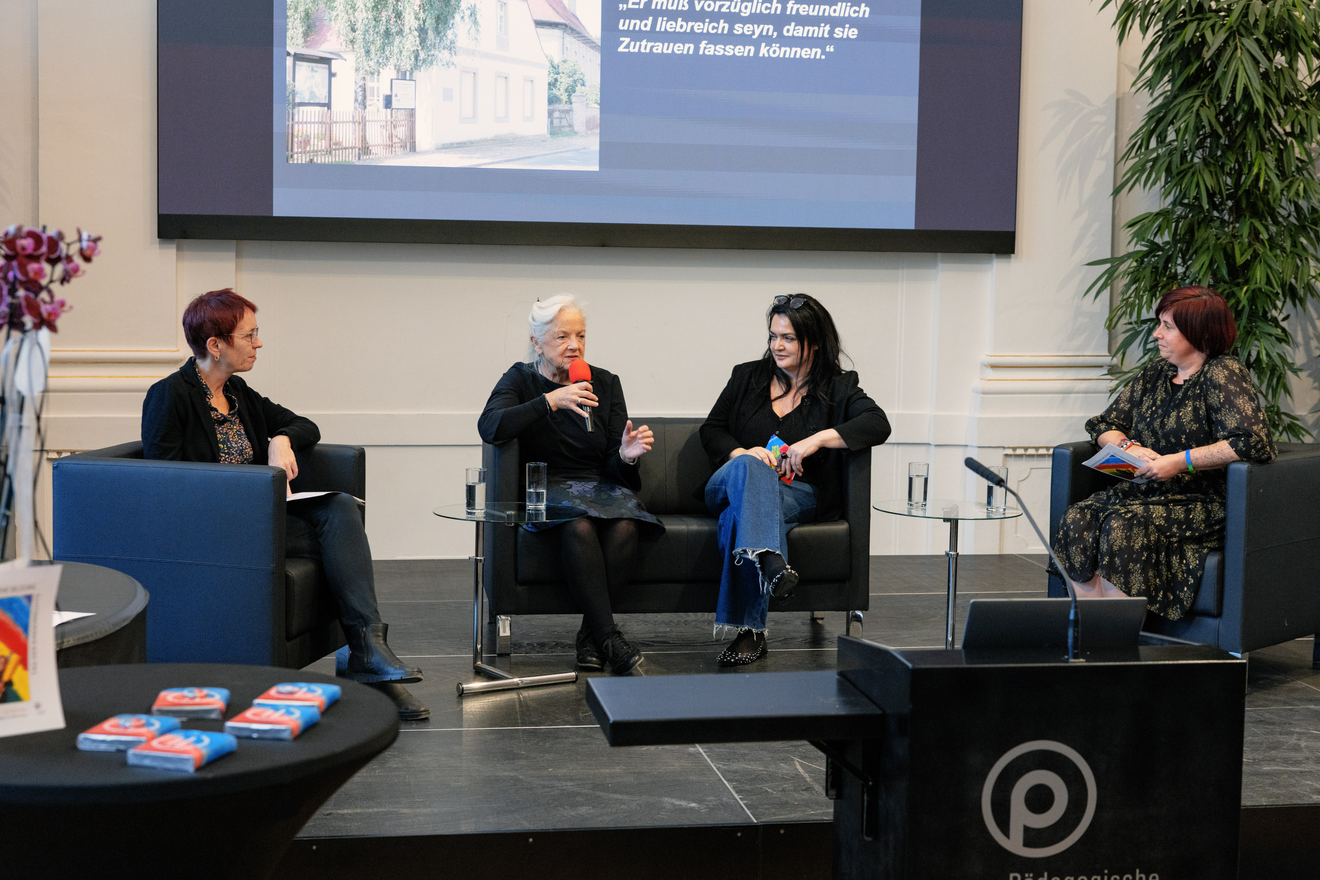 vier Personen sitzen auf der Bühne und diskutieren 