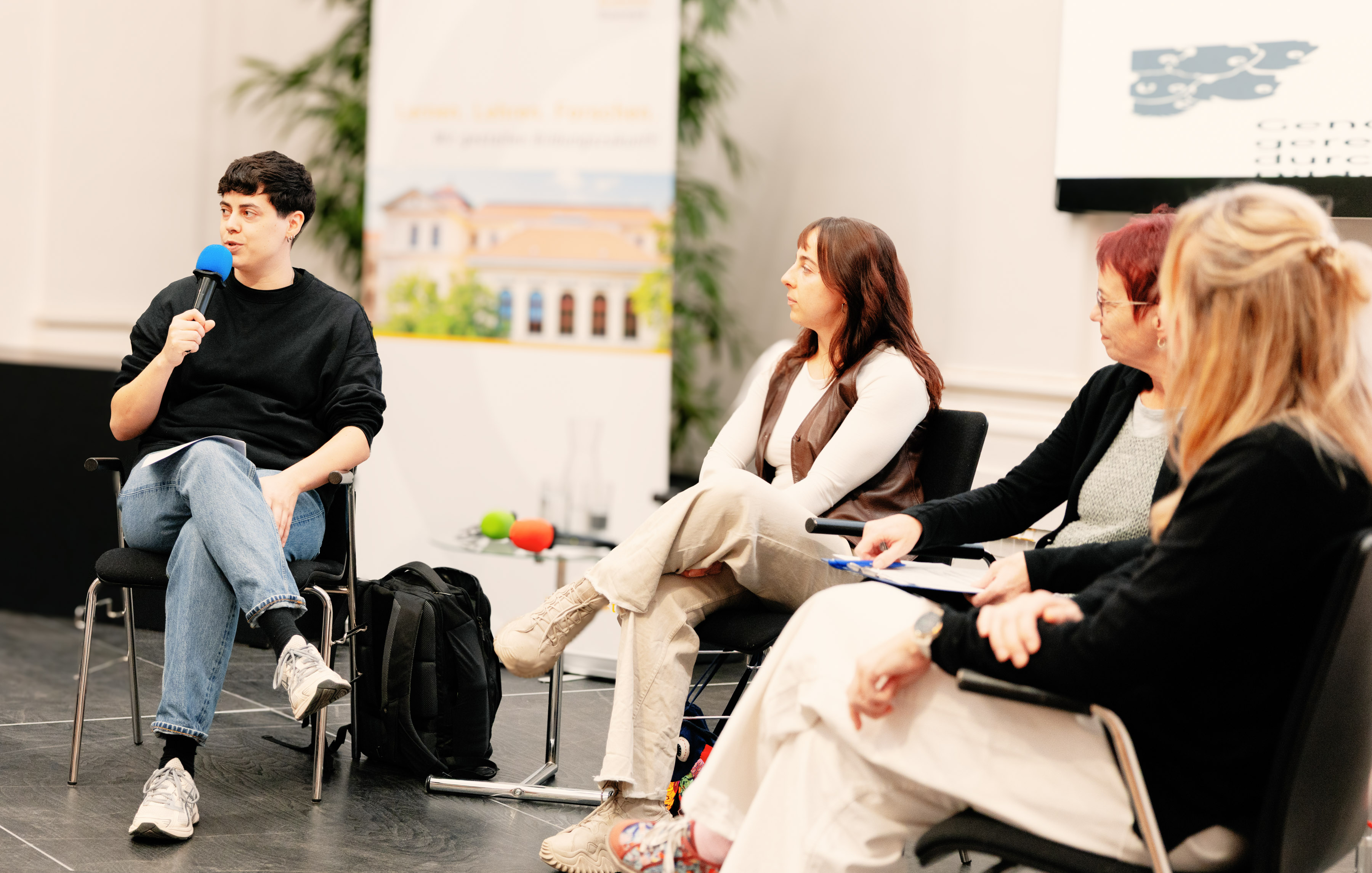 Personen sitzen auf Bühne und diskutieren 