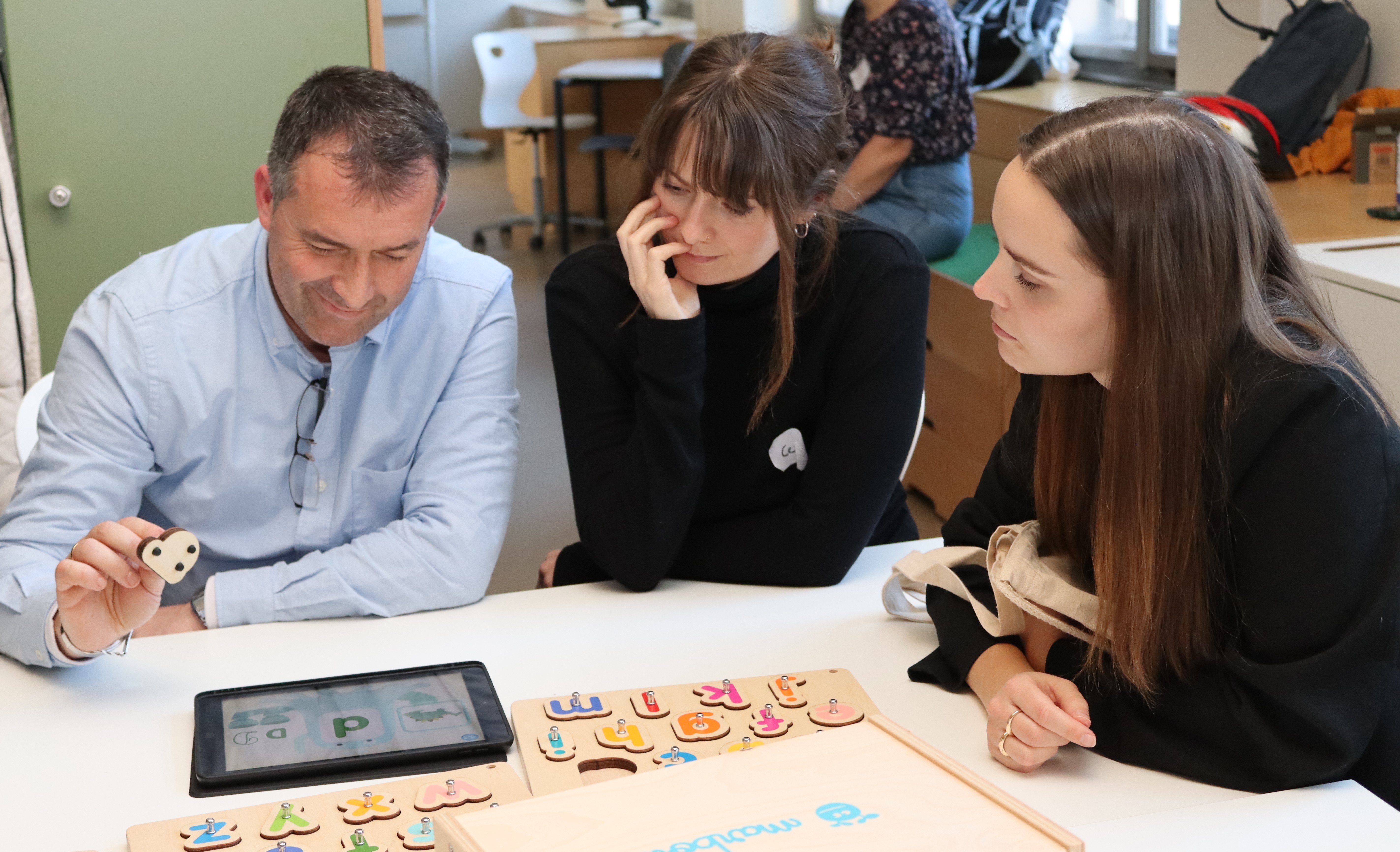 Drei Personen sitzen am Tisch 
