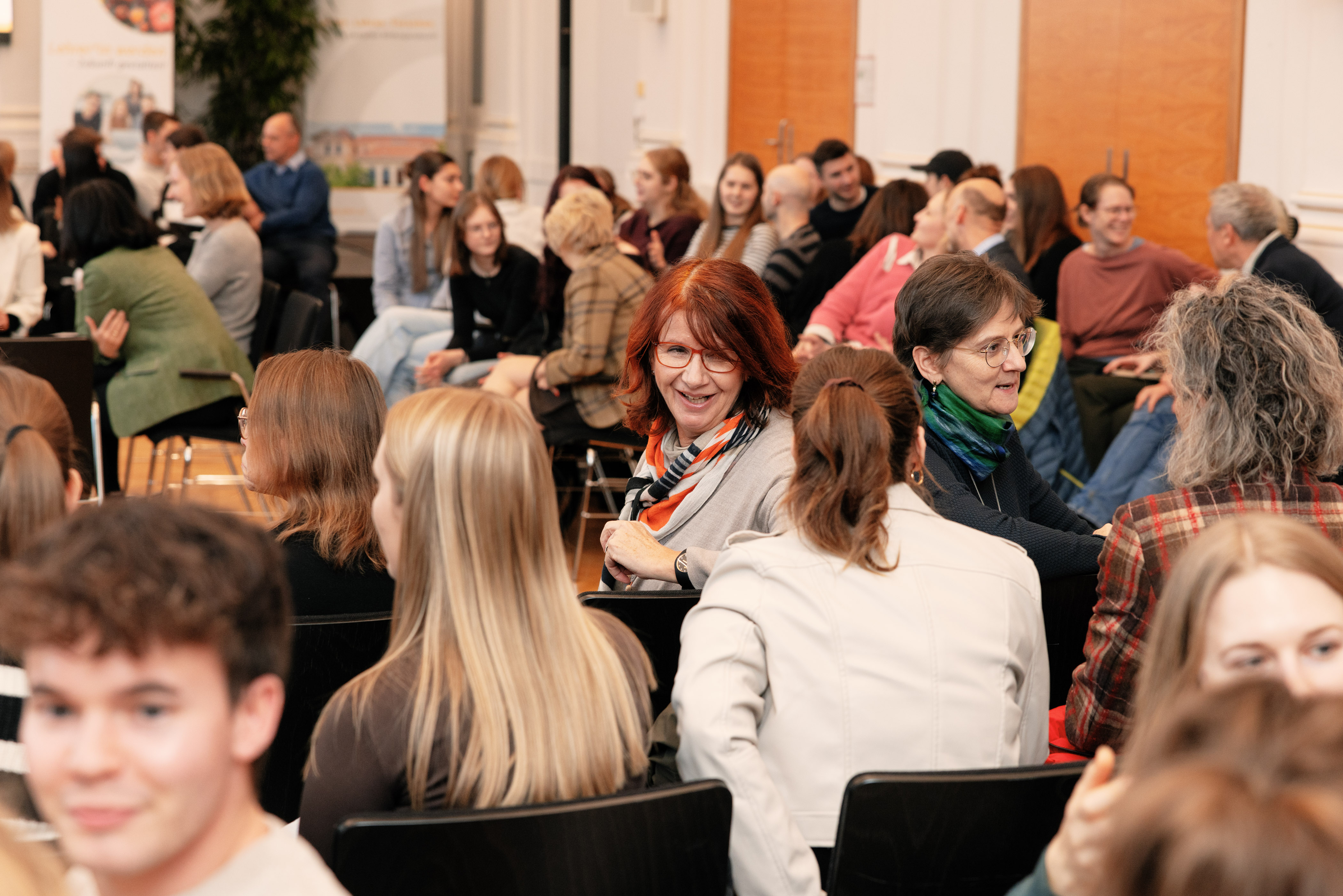 Personen sitzen im Publikum und reden miteinander