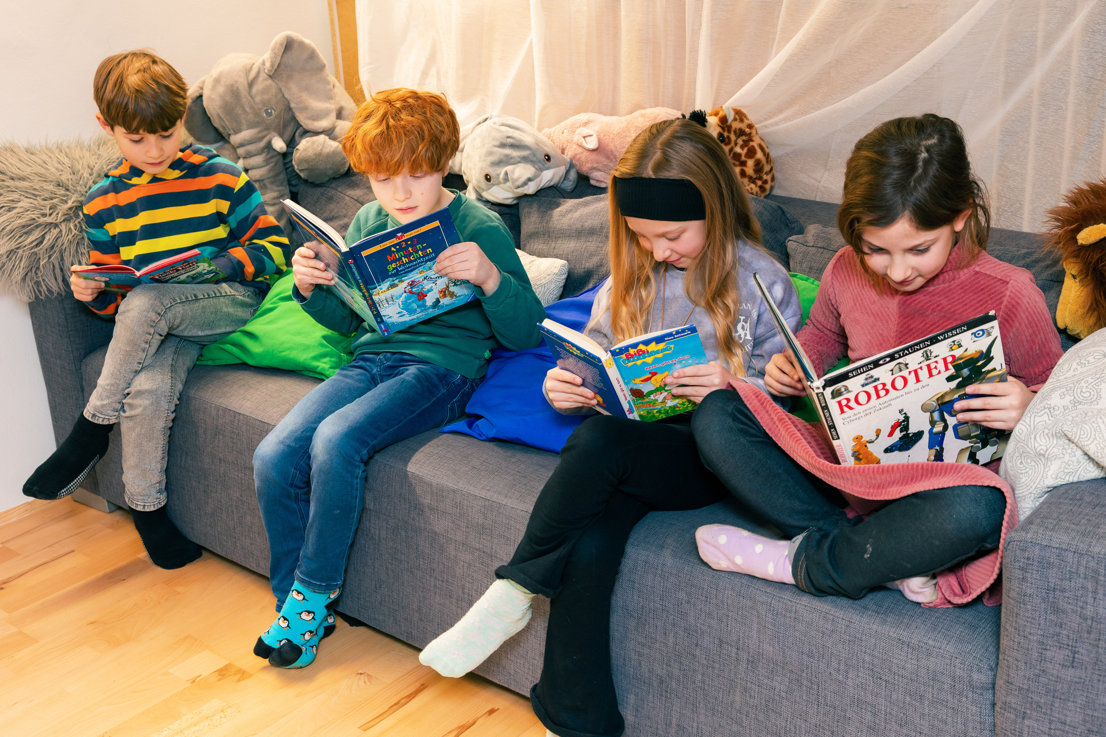 Kinder sitzen auf einem Sofa und lesen