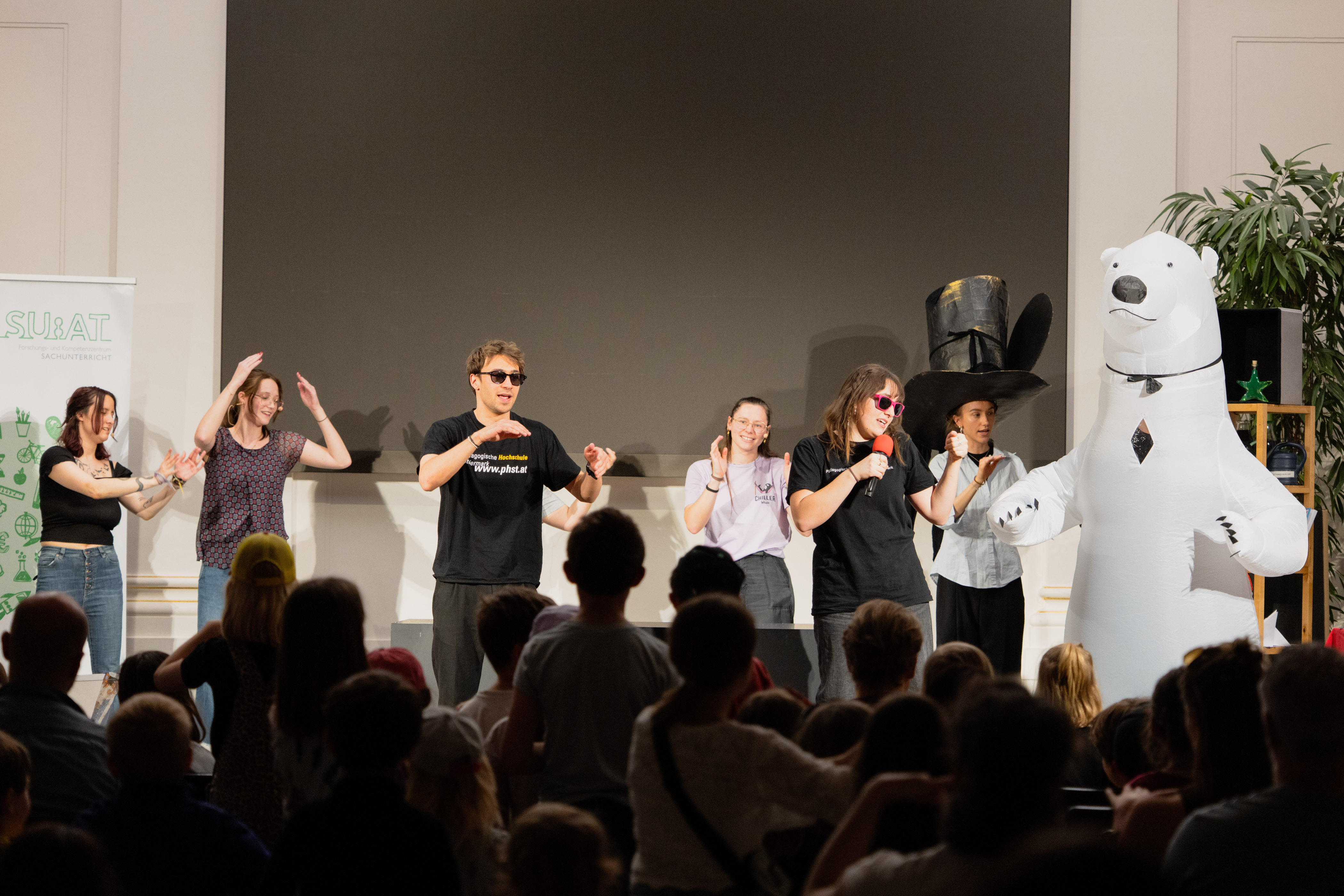 Mehrere Personen vor Publikum auf der Bühne beim Demonstrieren einer Station