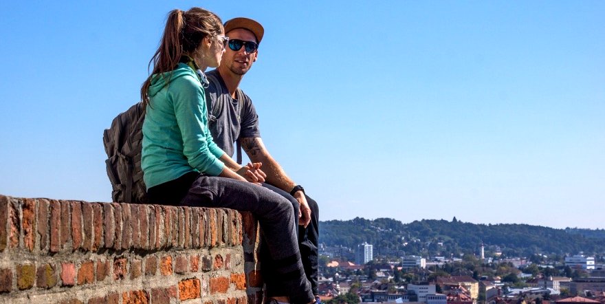 Frau und Mann sitzen auf einer Mauer