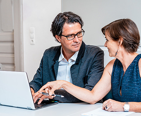 Personen schauen auf Laptop