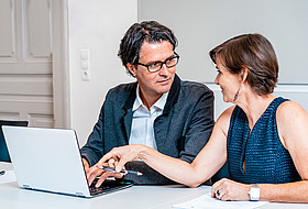 Personen schauen auf Laptop