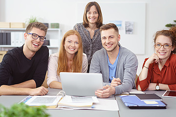 Symbolbild: 5 Studierende sitzen an einem Tisch mit Laptop und Lernunterlagen