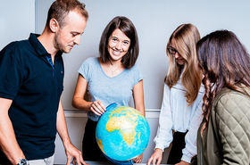 Vier Personen stehen vor einem Globus