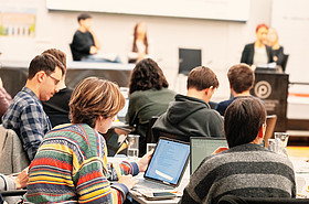 Personen sitzen am Tisch vor Laptops