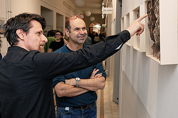 Zwei Männer betrachten eine Arbeit