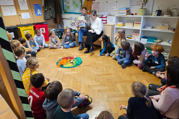 Zwei Studierende lesen Kindern Bücher vor 