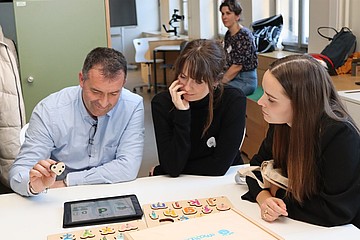 Personen sitzen am Tisch und probieren verschiedene Lernmaterialen aus
