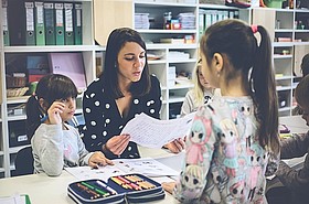 Lhererin erklärt zwei Schülerinnen etwas 