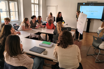 Studierende sitzen an Tischen