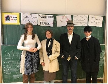 im Stil der 40er Jahre verkleidete Schüler*innen vor Tafel