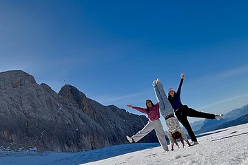 3 junge Frauen im Schnee machen Handstand vor Bergpanorma