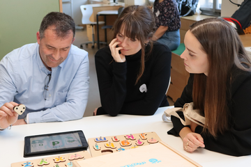 3 Personen sitzen am Tisch 