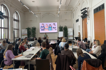 Personen sitzen in der Aula während Vortrag