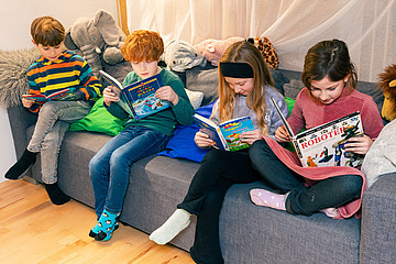 Kinder sitzen auf einem Sofa und lesen