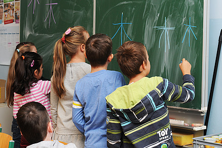 6 Kinder malen Sterne an die Tafel