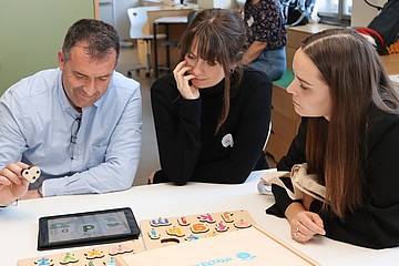 Drei Personen sitzen am Tisch 