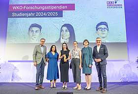 Viktoria Pauritsch mit Preis, Daniela Longhino, VR Elisabeth Amtmann und Vertreter WKO auf der Bühne, im Hintergrund Leinwand 
