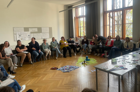 Personen sitzen in einem Sesselkreis