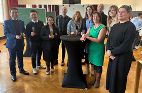 Personen stehen um einen Stehtisch herum