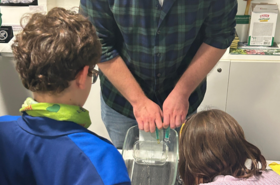 Mann zeigt ein Experiment vor Kindern